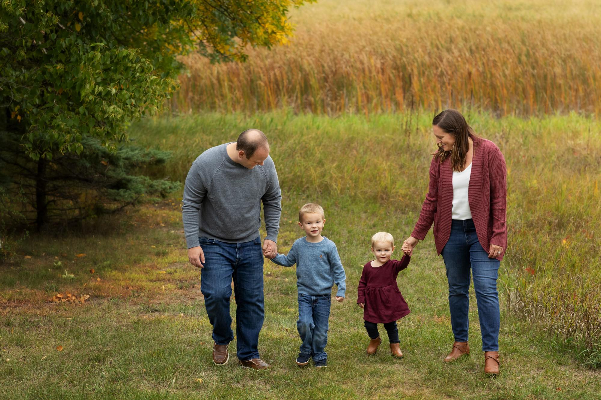 Young family walking in fall color during fall family session Monticello MN