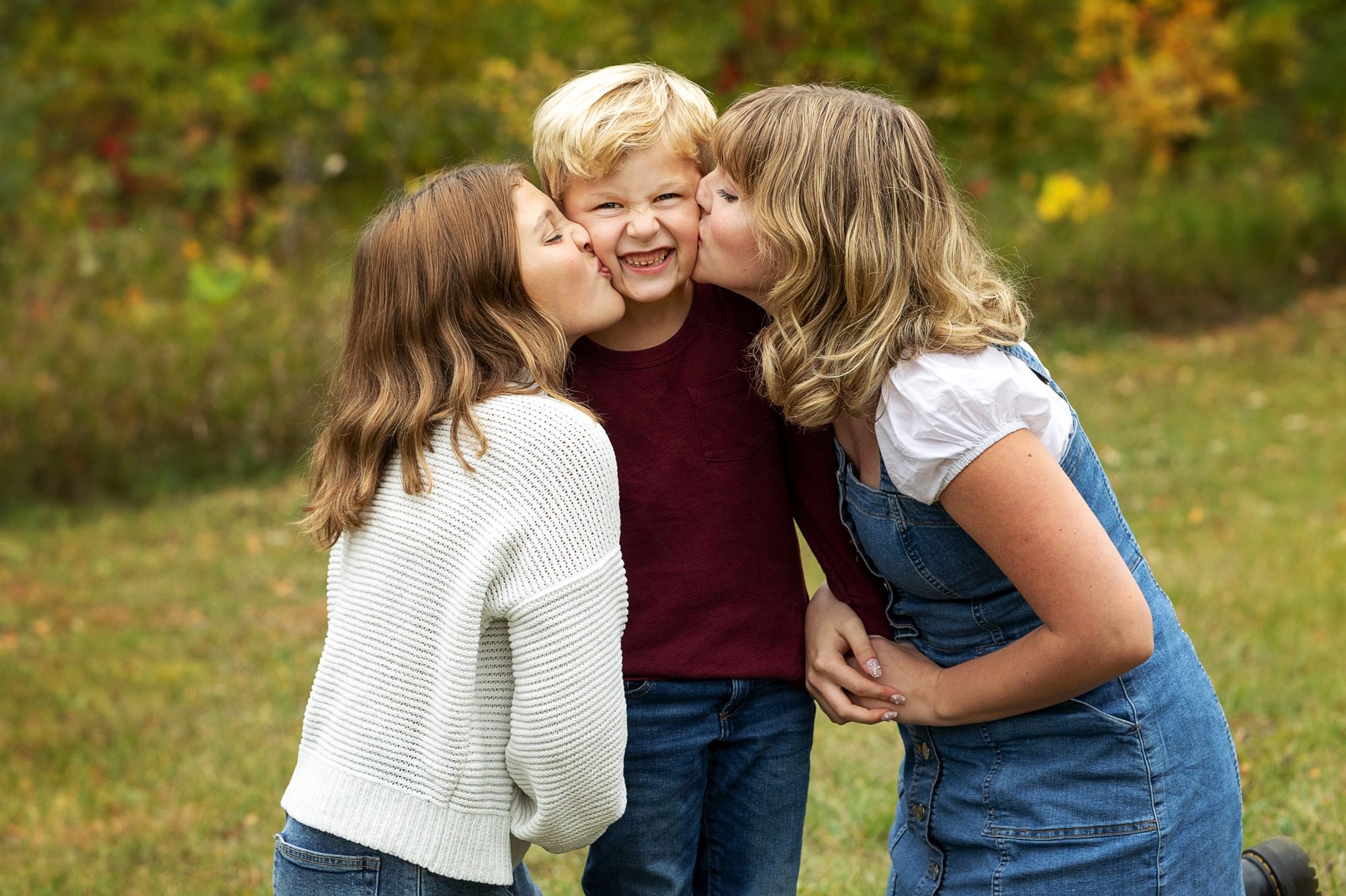 sisters kissing little brother during Minnesota fall family photos