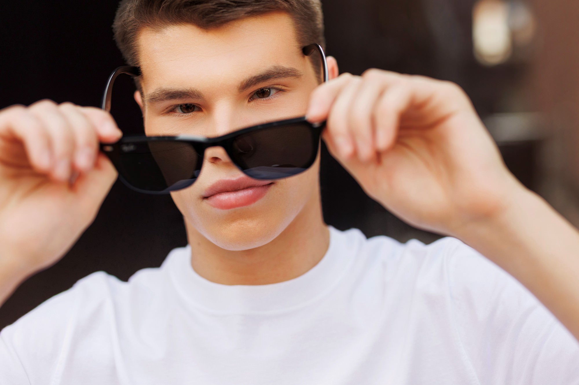 senior guy holding sunglasses during senior pics