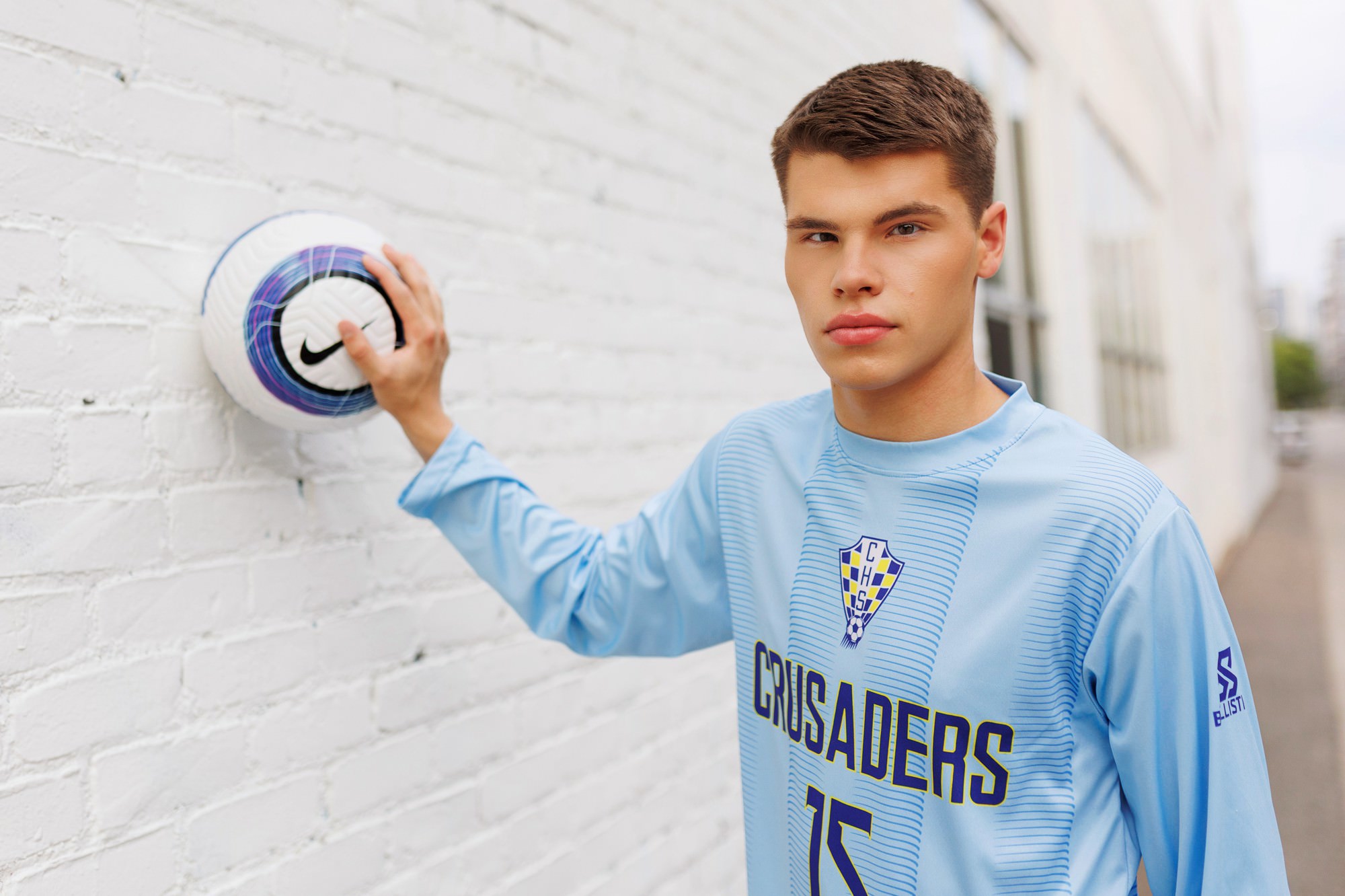 Senior boy with soccer jersey and ball in downtown Minneapolis alleyway
