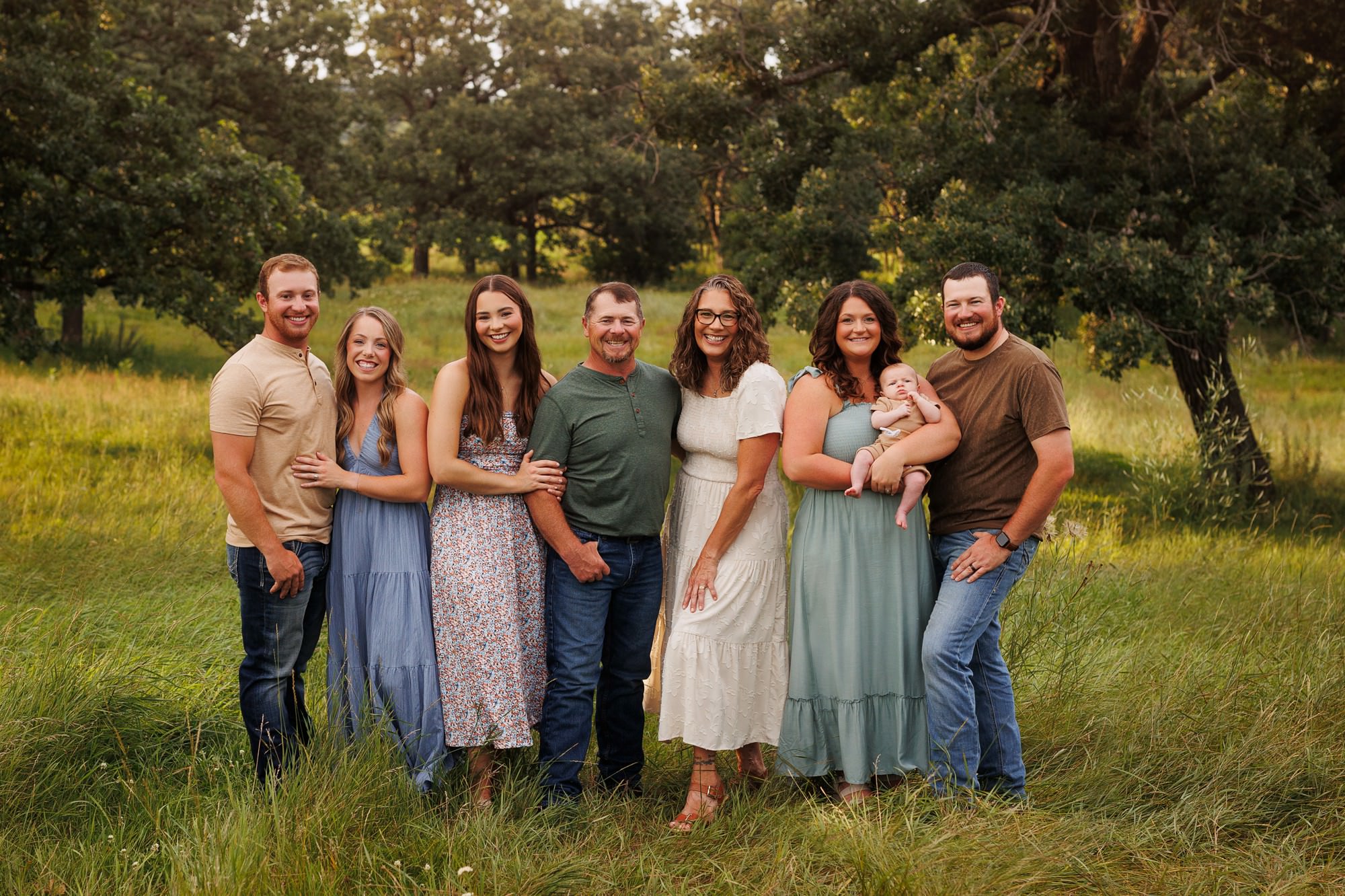 Multi-generation extended family portrait during an outdoor Minnesota family session in a grove of oak trees.